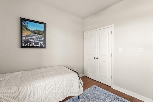 bedroom with dark hardwood / wood-style flooring and a closet