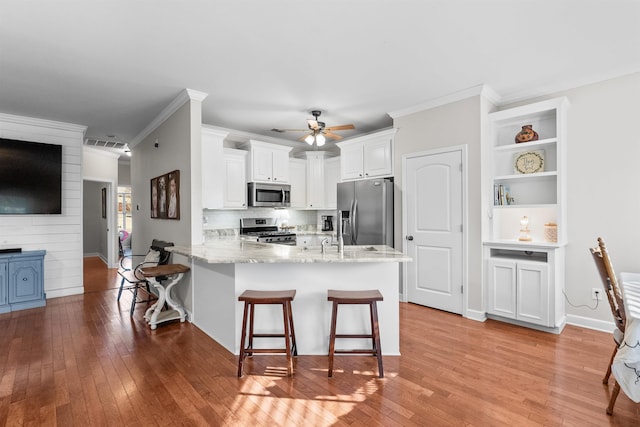 kitchen featuring stainless steel appliances, white cabinetry, a breakfast bar, and kitchen peninsula