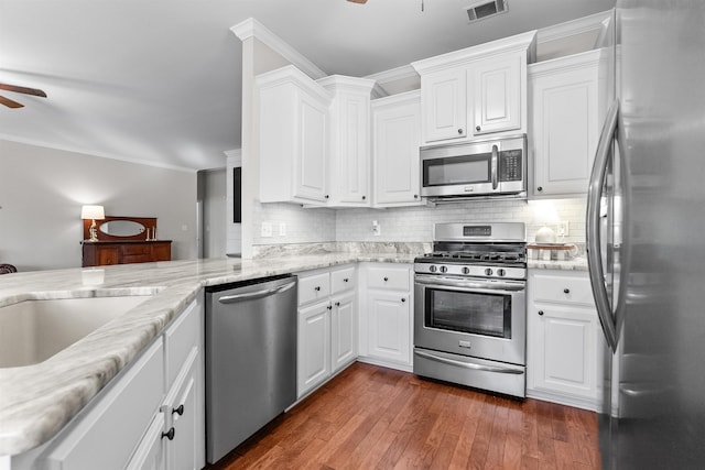 kitchen with white cabinetry, ornamental molding, ceiling fan, kitchen peninsula, and stainless steel appliances