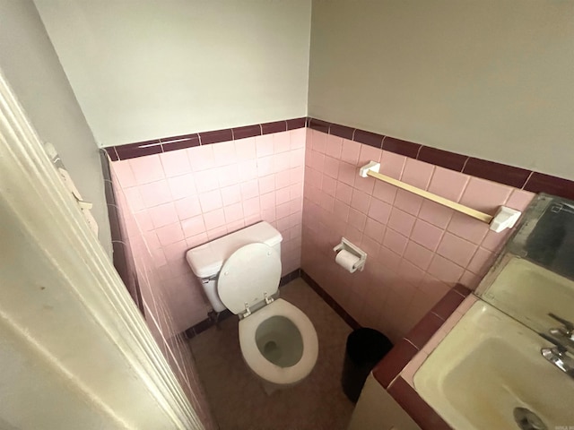 bathroom featuring sink, tile walls, and toilet