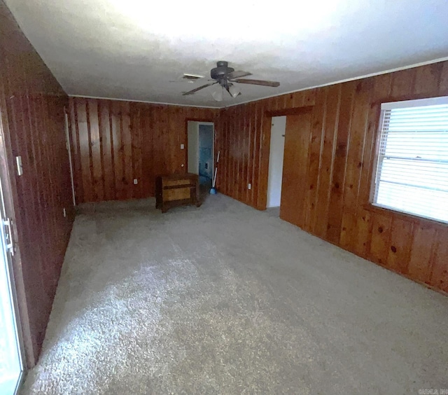 interior space featuring ceiling fan and wood walls