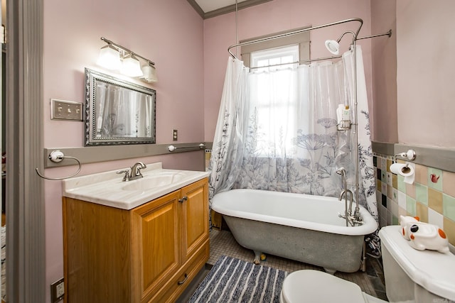 bathroom featuring toilet, tile walls, vanity, and a tub to relax in