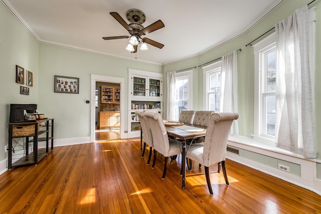 dining area with hardwood / wood-style flooring, ornamental molding, and ceiling fan