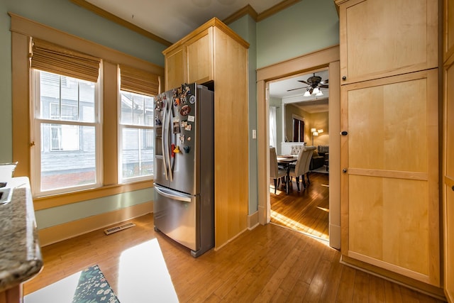 kitchen with light brown cabinets, light wood-type flooring, ornamental molding, and stainless steel refrigerator with ice dispenser