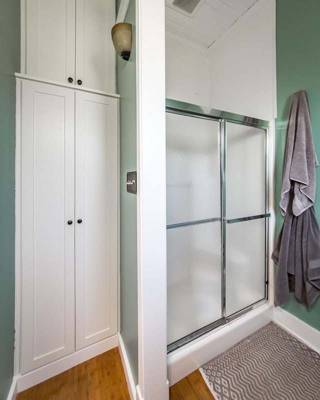 bathroom with an enclosed shower and hardwood / wood-style floors