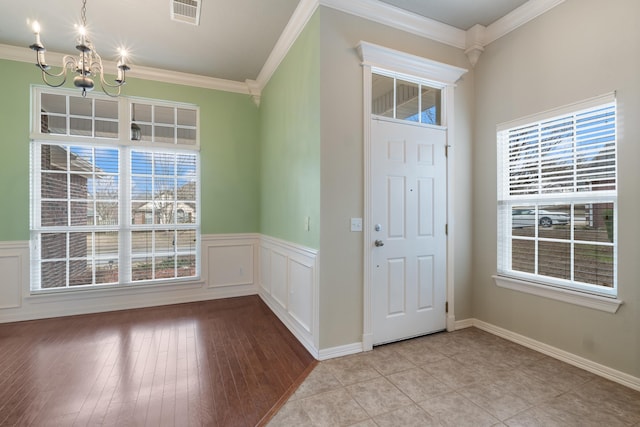 entryway featuring ornamental molding, a chandelier, light hardwood / wood-style floors, and a wealth of natural light