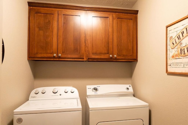 laundry room featuring cabinets, separate washer and dryer, and a textured ceiling