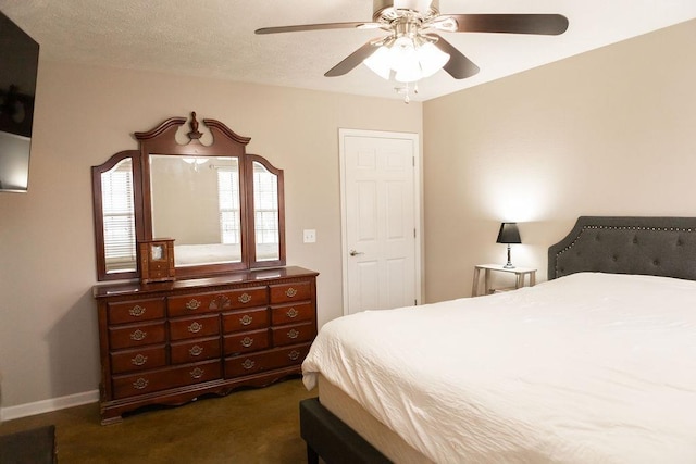 bedroom featuring ceiling fan, a textured ceiling, and dark carpet