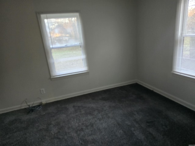 empty room with plenty of natural light and dark colored carpet