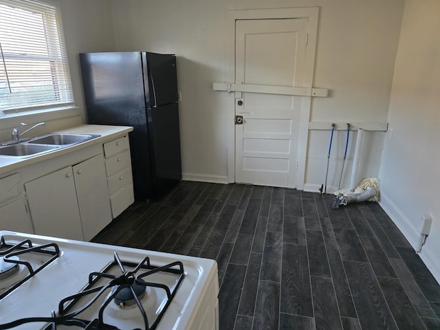 kitchen featuring white cabinetry, black refrigerator, sink, and white gas stove