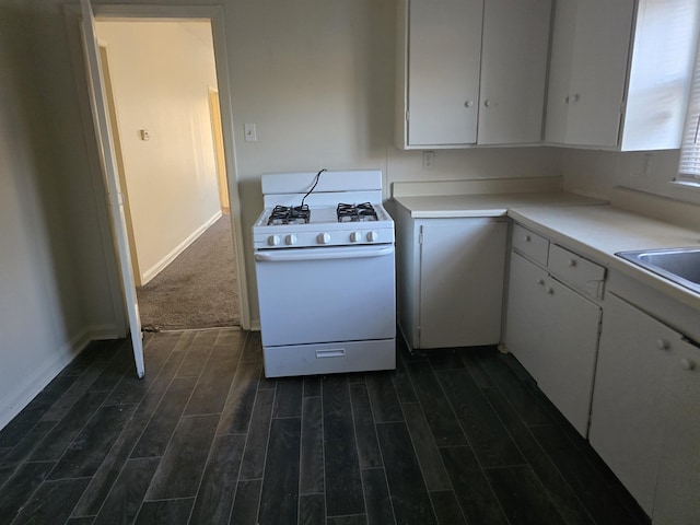 kitchen with sink, dark hardwood / wood-style flooring, white gas stove, and white cabinets