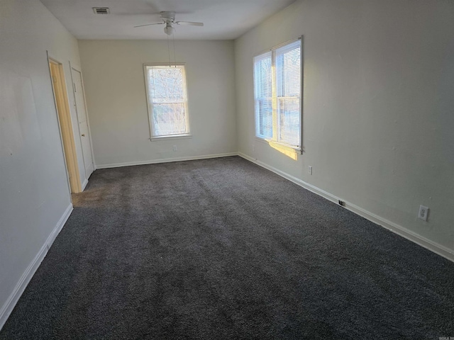 spare room featuring ceiling fan and dark carpet