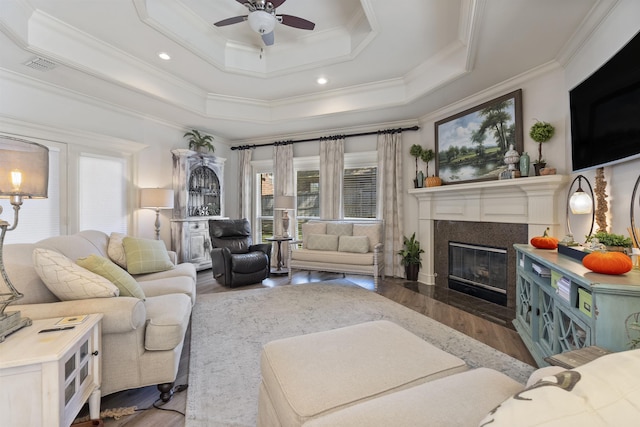 living room with hardwood / wood-style floors, crown molding, a raised ceiling, and ceiling fan