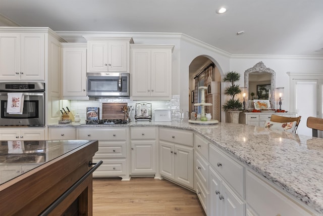 kitchen with stainless steel appliances, white cabinetry, and ornamental molding