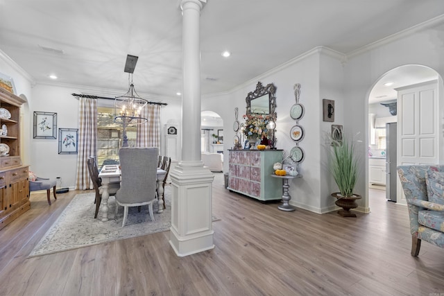 dining room featuring ornate columns, crown molding, a healthy amount of sunlight, and light hardwood / wood-style floors