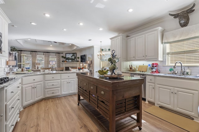 kitchen featuring stainless steel dishwasher, a raised ceiling, white cabinets, and light wood-type flooring