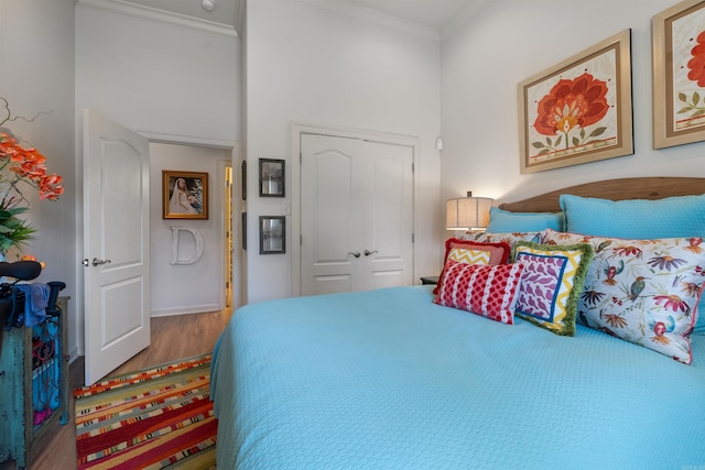 bedroom with hardwood / wood-style flooring, ornamental molding, and a closet