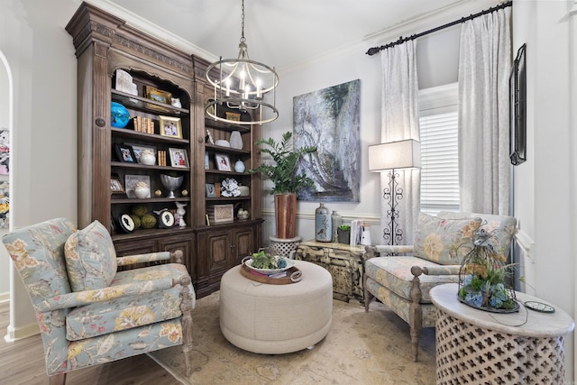 living area featuring an inviting chandelier, crown molding, and light hardwood / wood-style flooring