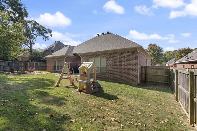 rear view of property featuring a playground and a yard