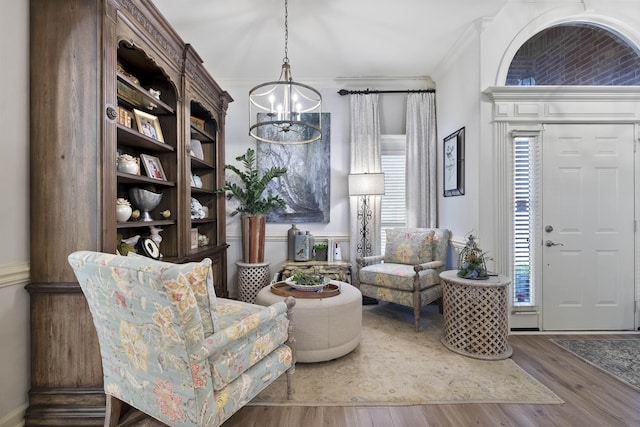 living area featuring ornamental molding, a chandelier, and hardwood / wood-style floors