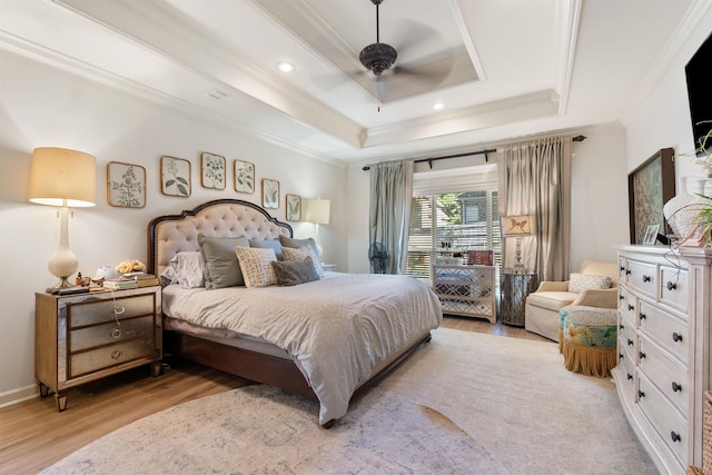 bedroom with ornamental molding, ceiling fan, light hardwood / wood-style floors, and a tray ceiling