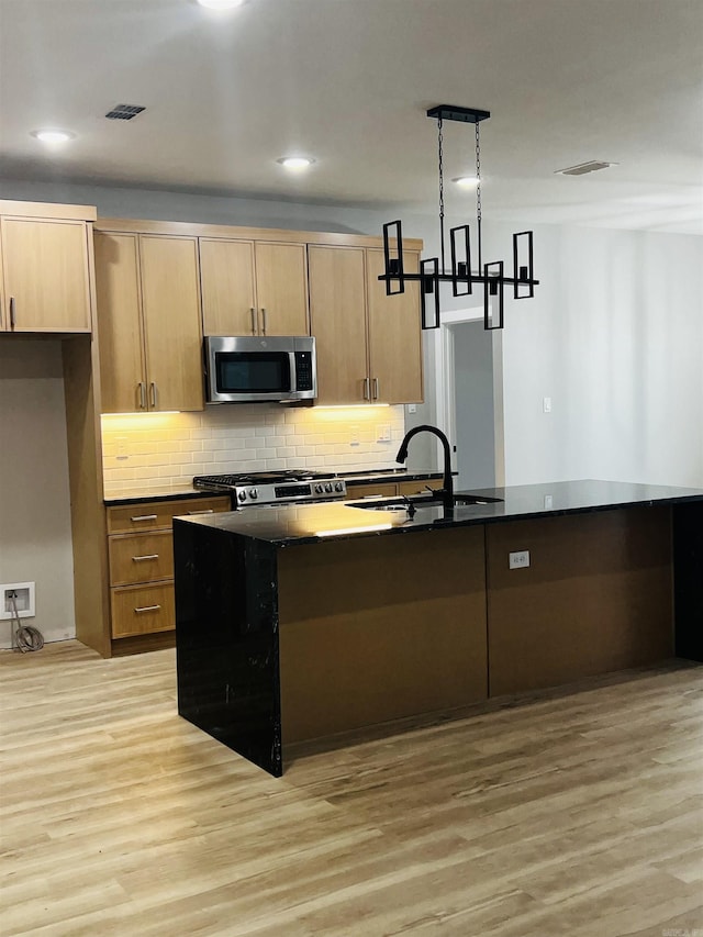 kitchen featuring pendant lighting, sink, range, a kitchen island with sink, and light hardwood / wood-style floors