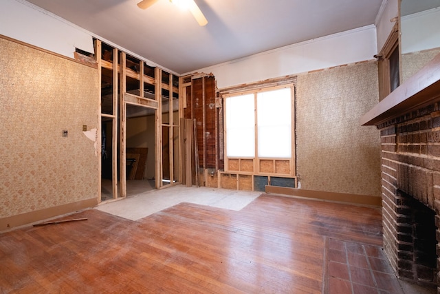 unfurnished room with ceiling fan, wood-type flooring, and a fireplace