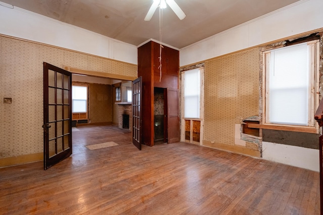 unfurnished living room with wood-type flooring, ornamental molding, and ceiling fan