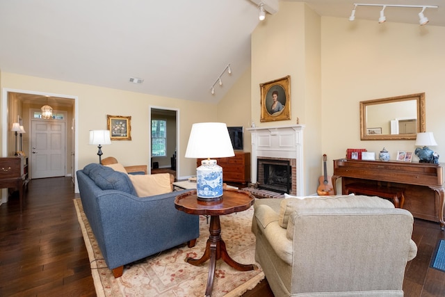 living room with rail lighting, high vaulted ceiling, dark hardwood / wood-style floors, and a fireplace