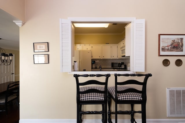 kitchen featuring tasteful backsplash, white appliances, and a kitchen breakfast bar