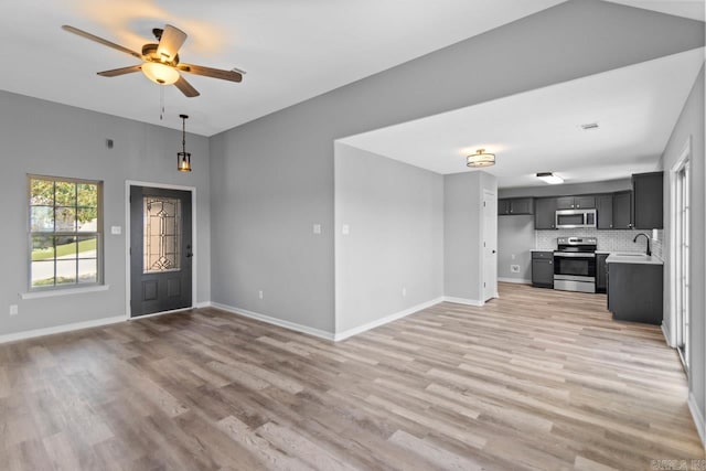 unfurnished living room featuring ceiling fan, sink, and light wood-type flooring