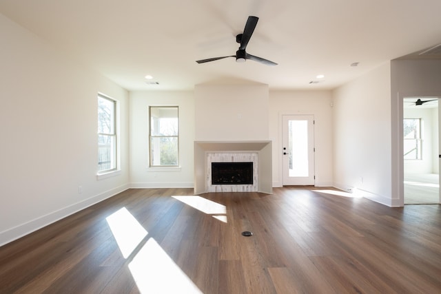 unfurnished living room featuring dark wood-type flooring, ceiling fan, and a tiled fireplace