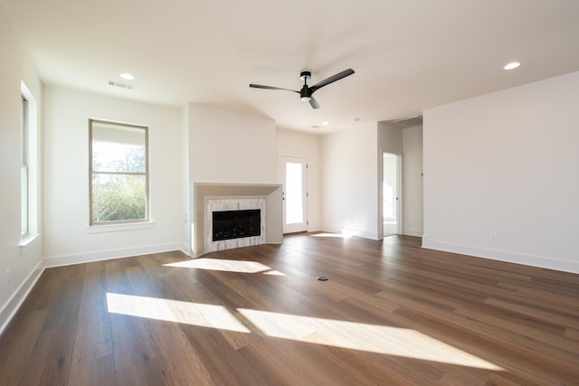 unfurnished living room with a tile fireplace, dark hardwood / wood-style floors, and ceiling fan