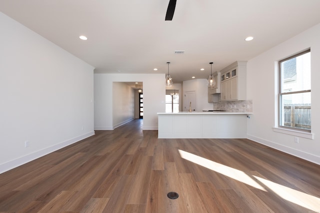 kitchen with dark hardwood / wood-style flooring, hanging light fixtures, backsplash, and plenty of natural light