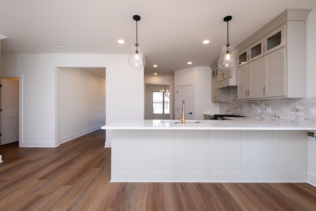 kitchen featuring sink, kitchen peninsula, dark hardwood / wood-style flooring, and decorative backsplash