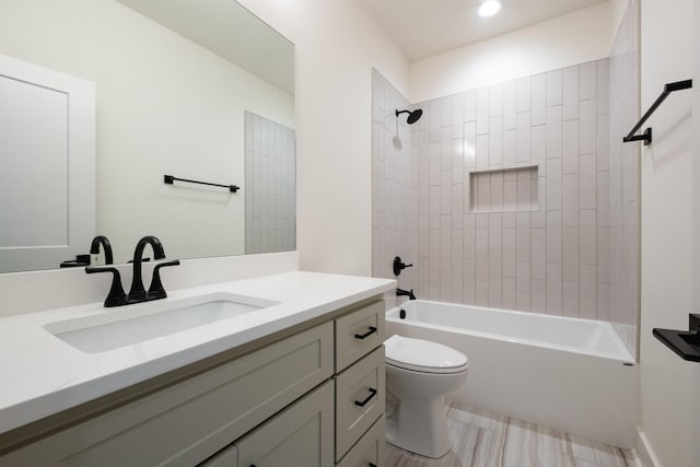 full bathroom featuring tiled shower / bath combo, vanity, and toilet