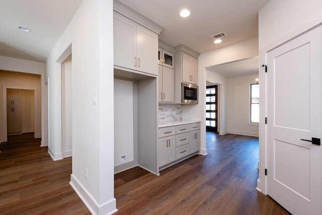 kitchen with built in microwave, dark wood-type flooring, tasteful backsplash, and white cabinets