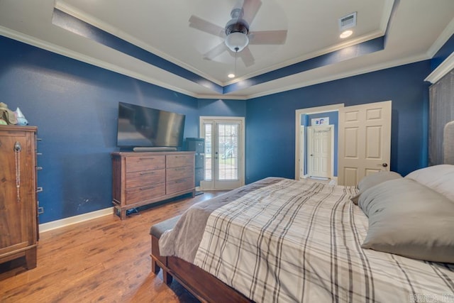 bedroom with hardwood / wood-style flooring, ornamental molding, and a raised ceiling