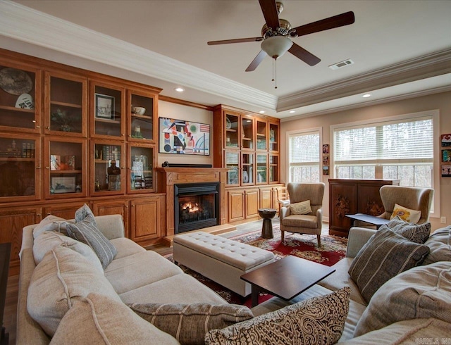 living room featuring a tray ceiling, wood-type flooring, ornamental molding, and ceiling fan