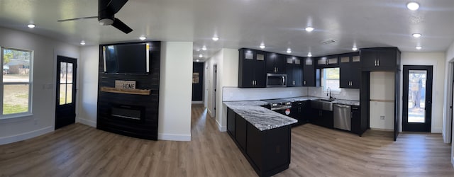 kitchen featuring sink, appliances with stainless steel finishes, backsplash, light stone counters, and light hardwood / wood-style floors