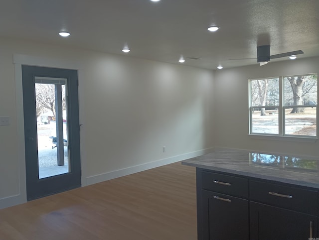 kitchen featuring ceiling fan, a healthy amount of sunlight, light stone counters, and dark hardwood / wood-style flooring