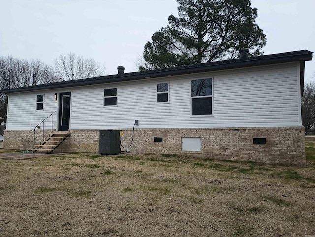 rear view of house featuring central AC and a lawn