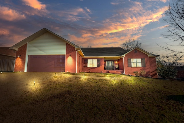 ranch-style home with a garage, a yard, and covered porch