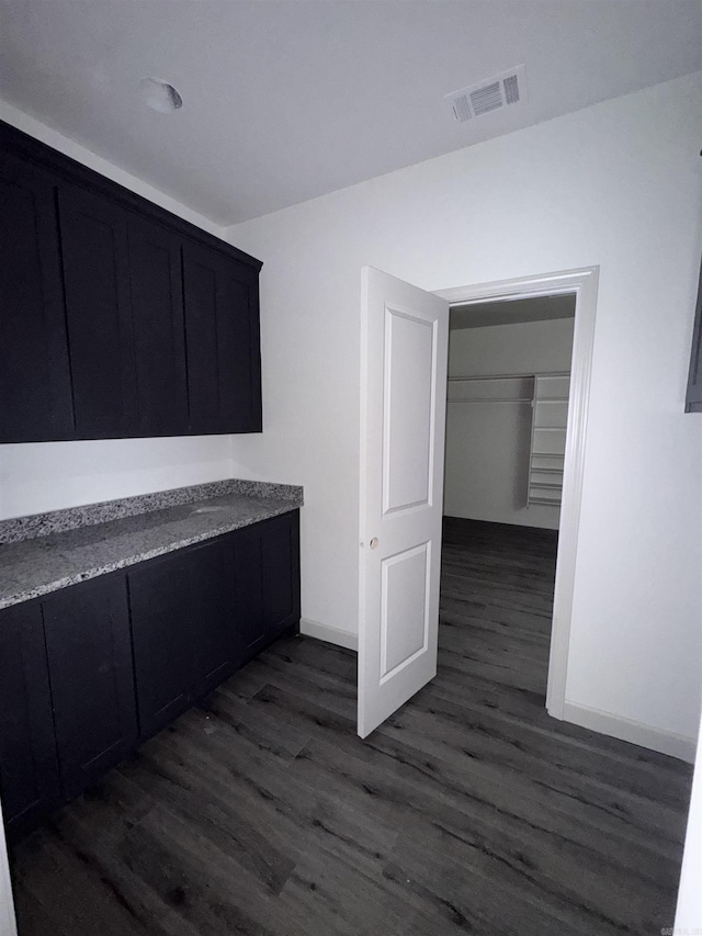 interior space with dark wood-style floors, visible vents, and baseboards