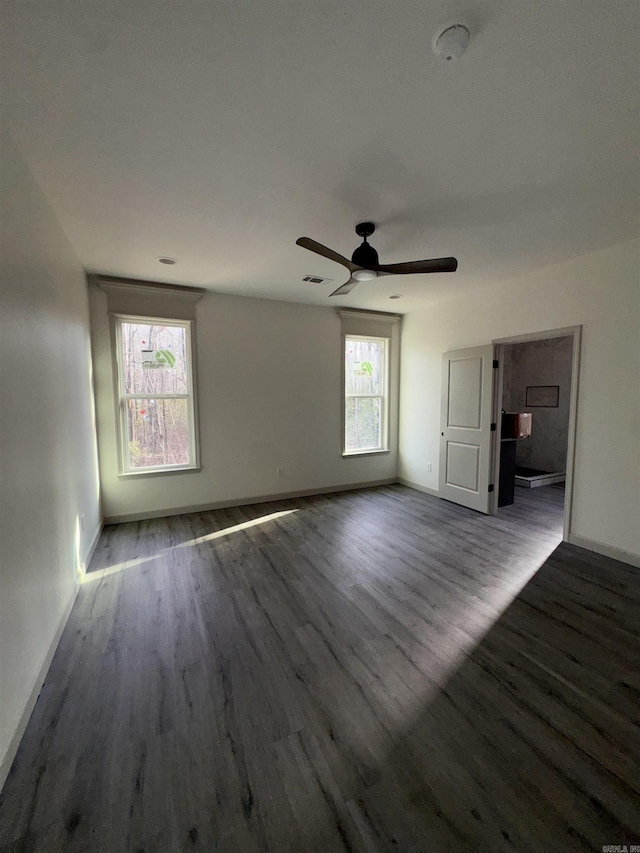 unfurnished living room with a ceiling fan, visible vents, baseboards, and wood finished floors