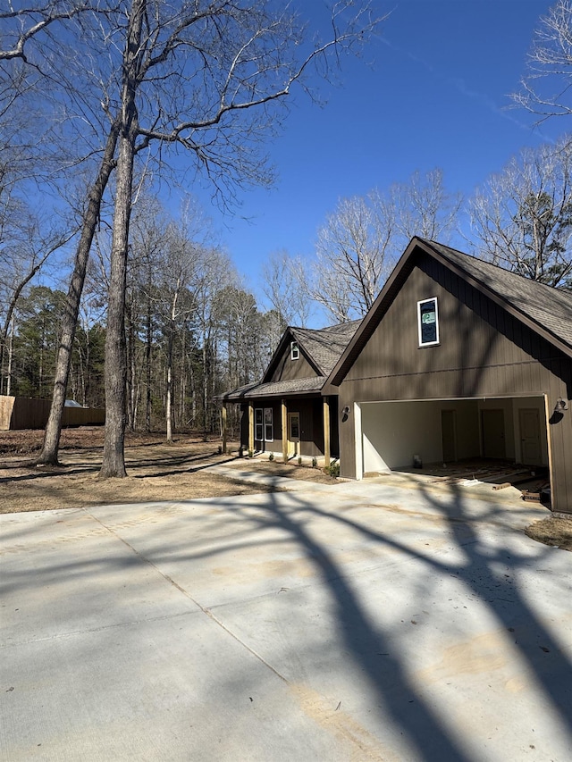 view of front facade with a porch, concrete driveway, roof with shingles, and an attached garage