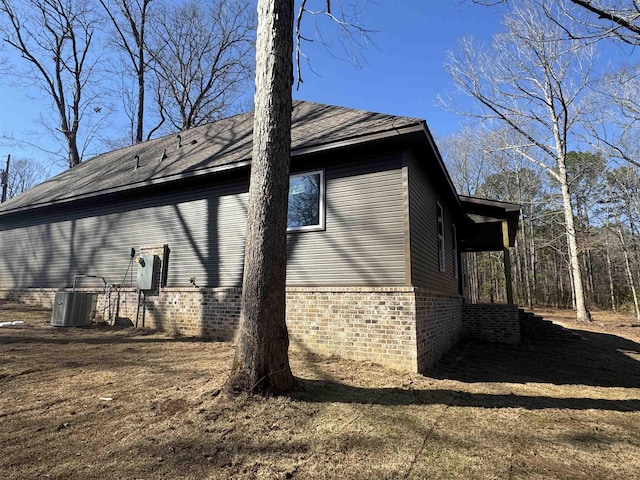 view of side of home with central AC unit and brick siding