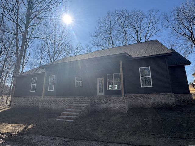 view of front facade with a shingled roof and brick siding