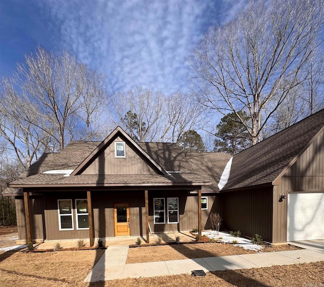 view of front of house with a garage, covered porch, and a shingled roof