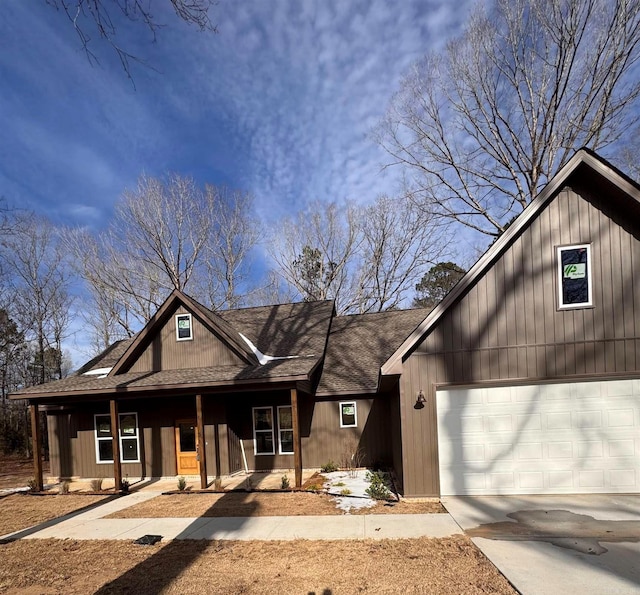 view of front of home with a garage, a porch, concrete driveway, and roof with shingles